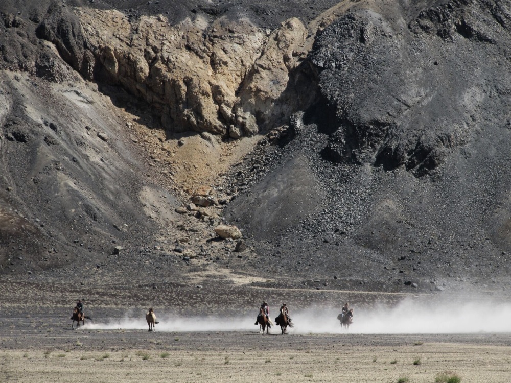 Reiter im Galopp vor Bergkulisse der Anden auf dem Ritt von Chile nach Argentinien.